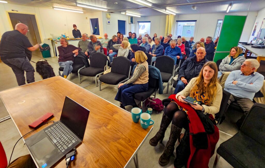 Group of fifty seated people in a small community hall
